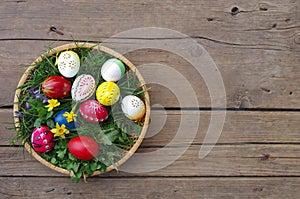 Colored Easter eggs in basket top view on wooden background. Happy Easter concept card. Happy Easter eggs on wooden background.