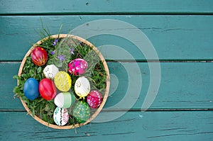 Colored Easter eggs in basket top view on wooden background. Happy Easter concept card. Happy Easter eggs on wooden background.