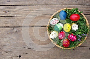 Colored Easter eggs in basket top view on wooden background. Happy Easter concept card. Happy Easter eggs on wooden background.