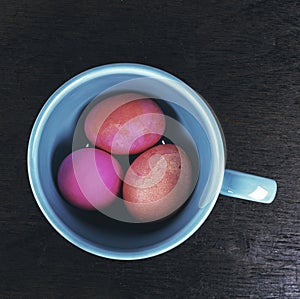 Colored easter eggs in ceramic cup on wooden background - vintag