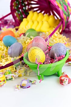 Colored Easter eggs, chicks, candy and basket