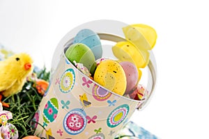 Colored Easter eggs, chicks, candy and bucket on grass
