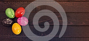 Colored easter eggs on dark wood background. View from above. Copy space for text
