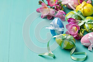 Colored Easter eggs and flowers on a turquoise table