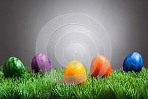 Colored easter eggs in grass, gray background