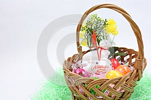 Colored Easter eggs and white lamb in a wicker basket
