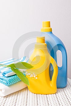 colored fabric clothes, lily of the valley flower, washing gel and fabric softener on a captive basket