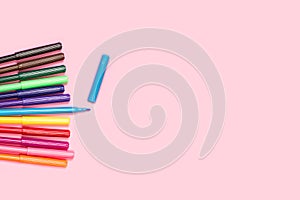 Colored felt tip pens, one open, on a pink background