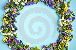 Colored flowers on blue background composition, circle shape. Flat lay