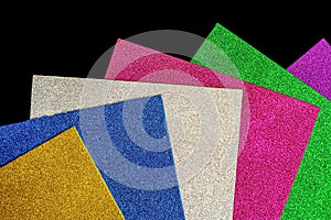 Colored foamiran sheets with sparkles on black background