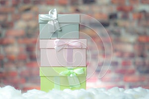 Colored gift box presents on white snow, background brick wall