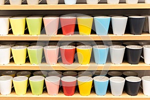 Colored glasses on the shelves in the store. ups of all colors of the rainbow on the counter of the store