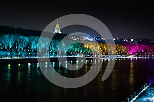 Colored illuminated trees by the river. Russia, Moscow