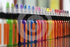 Colored inks in plastic containers formed in a row and bokeh background photo
