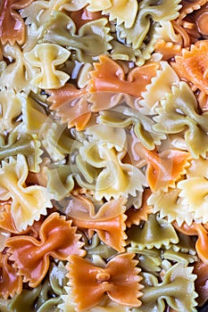 Colored italian cooked pasta farfalle tricolore abstract backdrop.