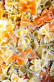 Colored italian cooked pasta farfalle tricolore abstract background.