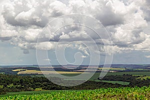 Colored landscape below bright colossal clouds