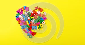 colored letters of the alphabet in the shape of a heart on a yellow background