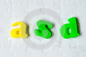 Colored letters ASD on a background of white puzzles. World autism awareness day concept