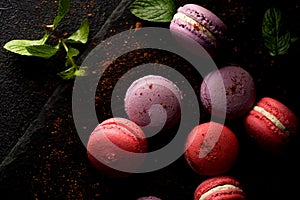 Colored macaroons. Delicious sweet colorful French desserts on black background