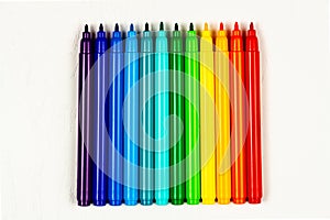 colored markers without caps lie on a white wooden table