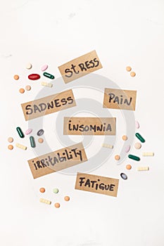 Colored medical pills and capsules and labels with illness names on a white background