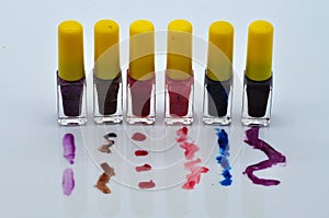 Colored nail polishes on spilled content splashes on white background.