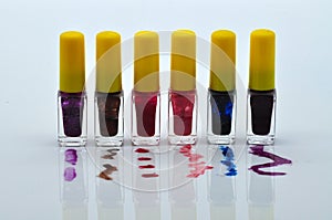 Colored nail polishes on spilled content splashes on white background.