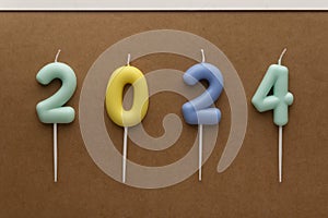 Colored numbers of year 2024 made from candles on brown background. Holiday background Happy New Year 2024. Celebrating New Year