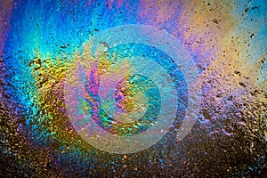 Colored oil stain on the asphalt. A rainbow slick of gasoline. Abstract background