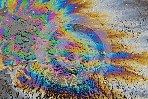 Colored oil stain on the asphalt. A rainbow slick of gasoline. Abstract background