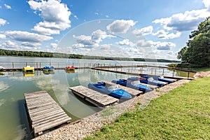 Colored old vintage plastic catamarans and boats near a wooden pier on the shore of a large lake