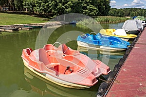 Colored old vintage plastic catamarans and boats near a wooden pier on the shore of a large lake