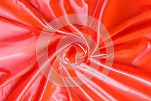 Colored orange textile satin fabric folded in folds and waves with highlights and texture