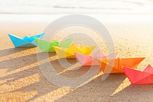 Colored paper boats row on sandy beach outdoors