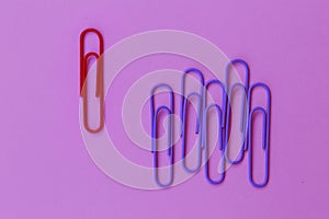 Colored paper red clip outstanding on purple background. minimal