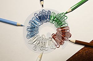 Colored paperclips in a circle and pencils