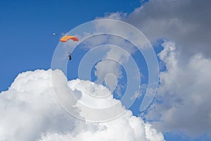 Colored parachute jumper tandem on a blue sky over clouds