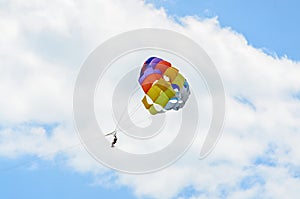 Colored parasail wing in the blue clouds sky, Parasailing