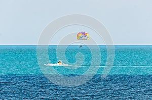 Colored parasail wing pulled by a boat in the sea water, Parasailing also known as parascending or parakiting