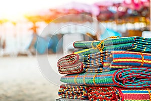 Colored patterns of traditional matting beach matting folded in a stack against the backdrop of the sea and sun.