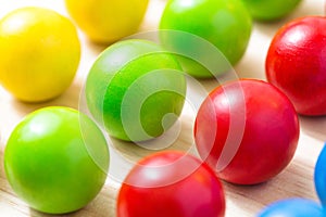 Colored pegs board, wood beads on wooden background.