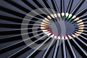 Colored pencil set arranged in circle on black background. Stationery minimal round frame