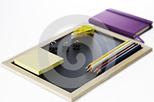 Colored pencils, black board, notebook and memopad photo
