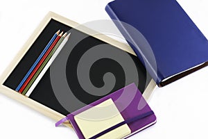 Colored pencils, black board, notebooks and memopad photo