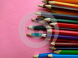 Colored pencils are broken on a pink background. Many different colored pencils. Colored pencil. The pencils are broken