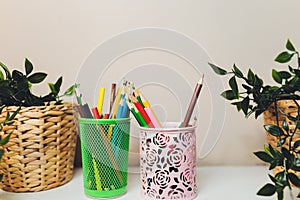 Colored pencils, brushes for drawing, eraser and ruler in a transparent black metal cup. Education concept