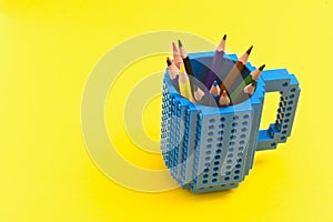 Colored pencils in a bucket on yellow background. Back to scool concept photo