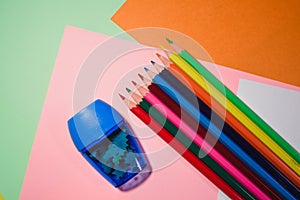 The colored pencils on a colorful background with pencil sharpener