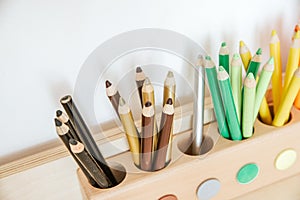 Colored pencils in a container on a wooden table, close up on brown